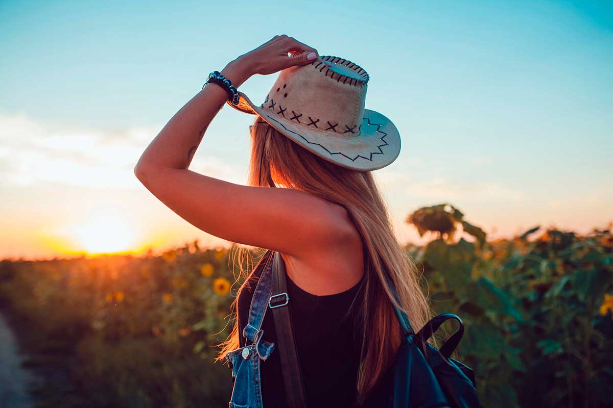 Woman in a cowboy hat in a sunflower field in Texas.