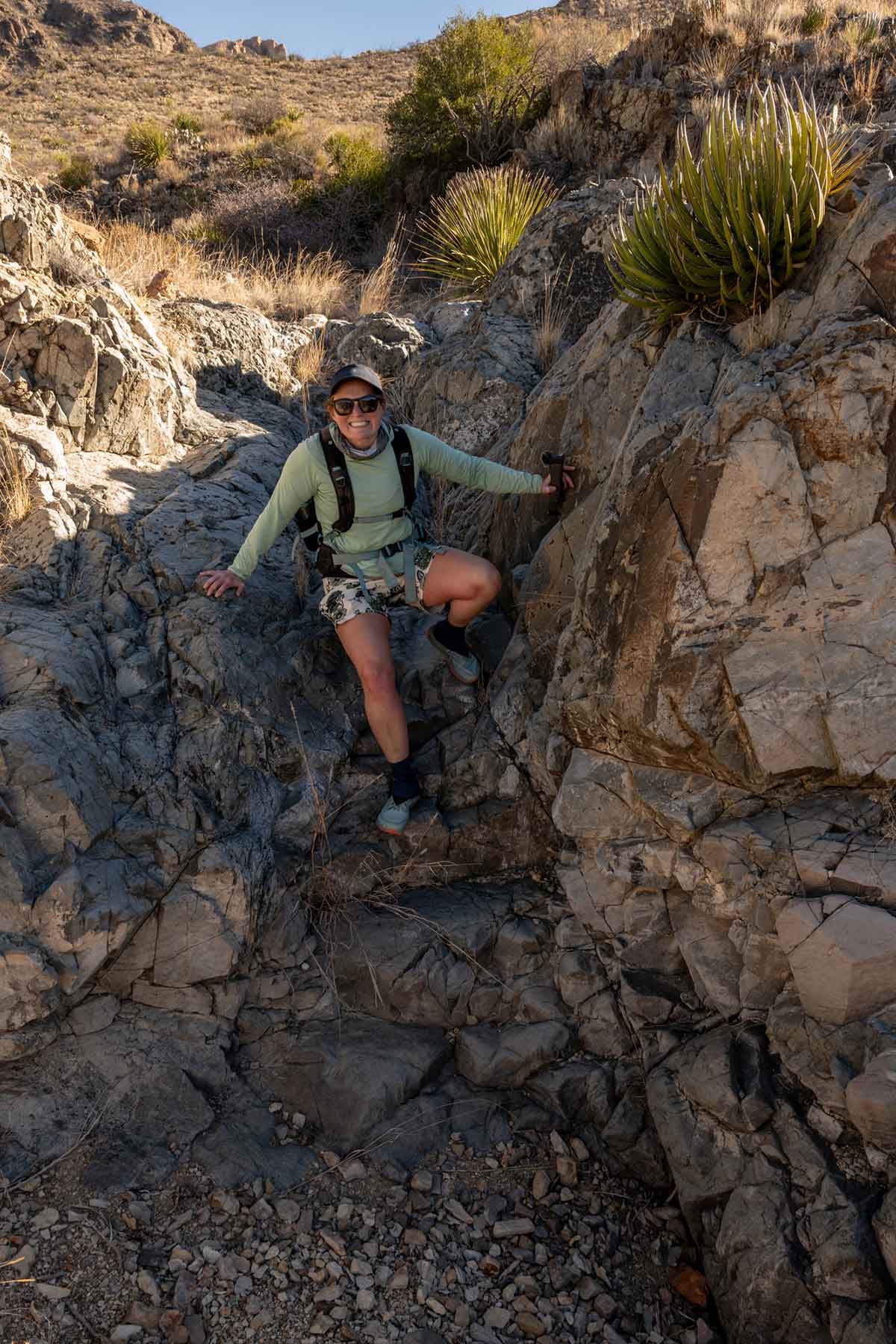 Woman grins as she Downclimbs a dry Fall in Big Bend National Park.