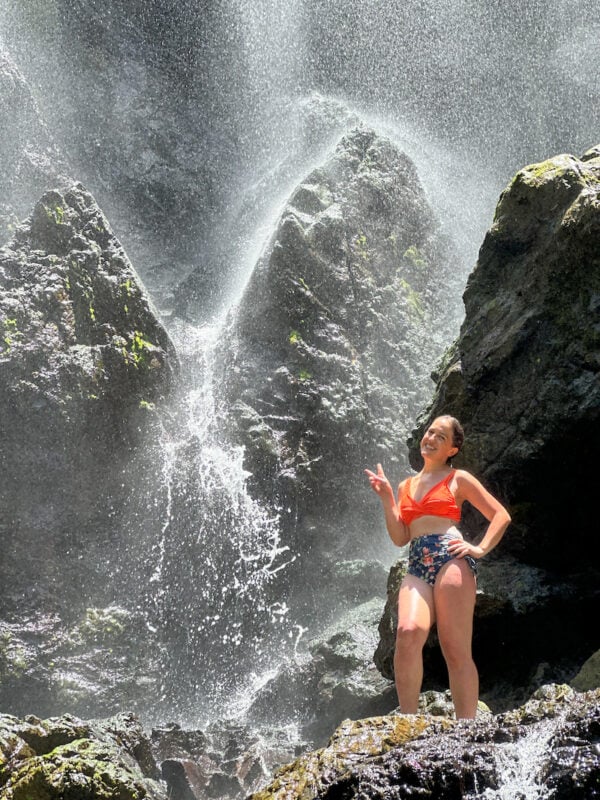 woman in an orange bathing suit climbing the rocks around Charco Prieto Waterfall