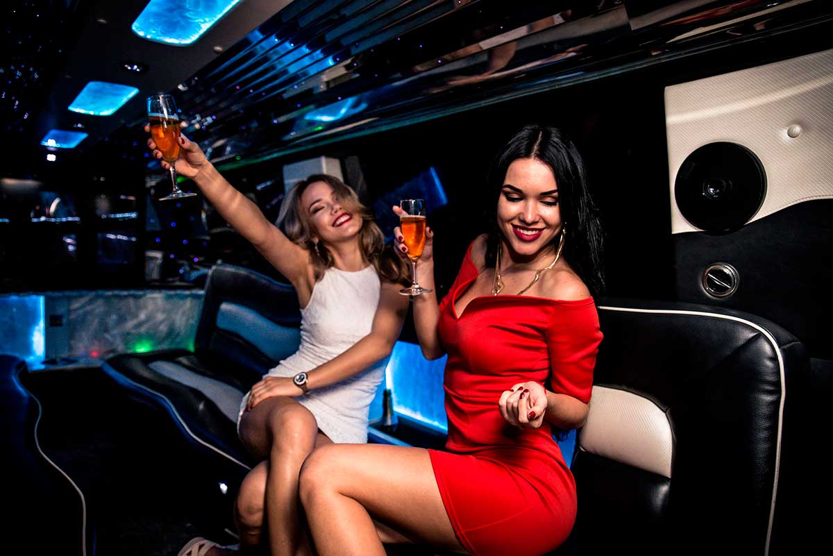 Two women drinking rose on champagne glasses on an NYC limo tour.