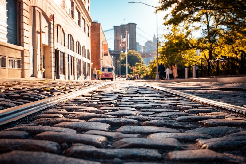 cobblestone street in DUMBO with a view of the Brooklyn Bridge in the background