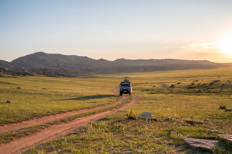 Russian Furgon van driving through the Mongolian Gobi Desert at sunset