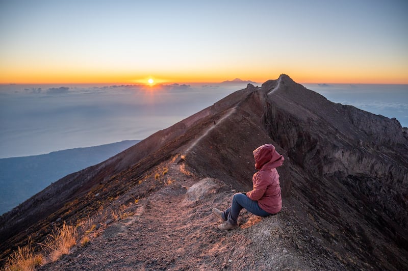 female traveler watching the sunrise from the summit of Mount Agung in Bali