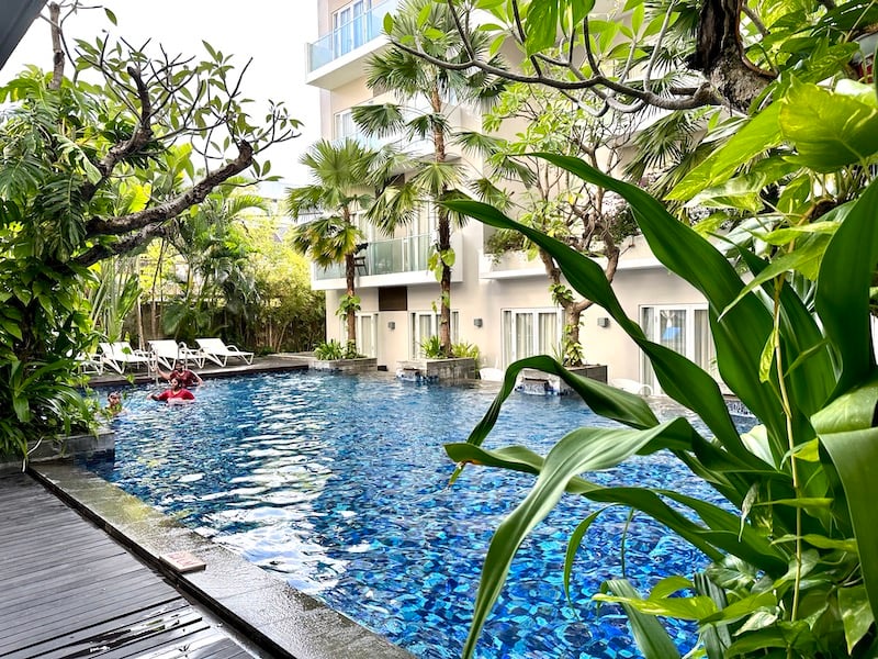 Pool surrounded by lush plants at Grand Ixora Kuta Resort