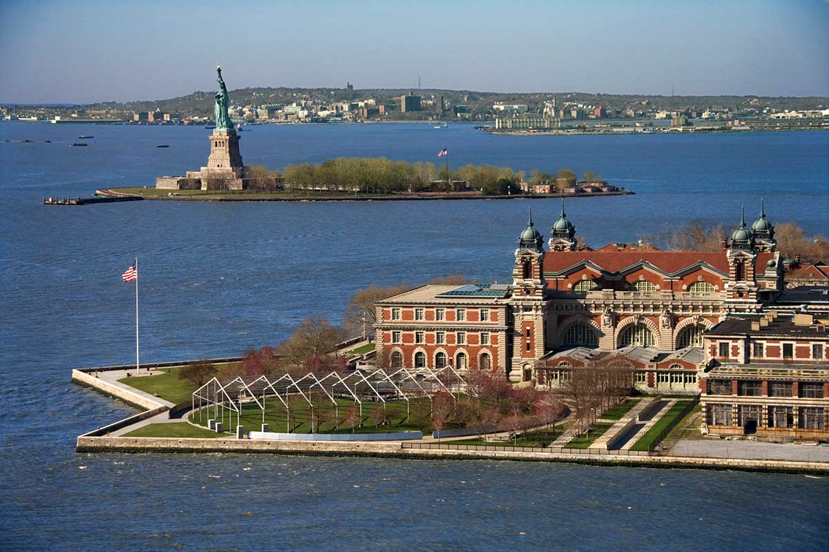 A photo of Ellis Island and its Museums as well as the Statue of Liberty in the background.