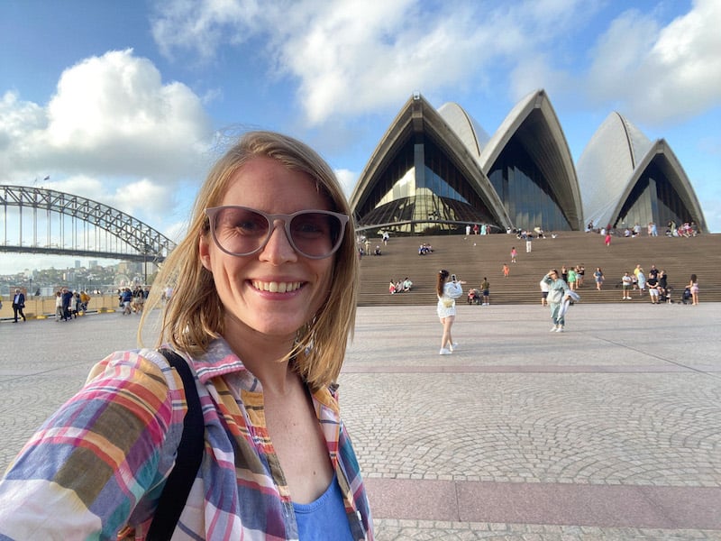 solo female traveler in Sydney taking a selfie in front of the Sydney Opera House and the Harbour Bridge