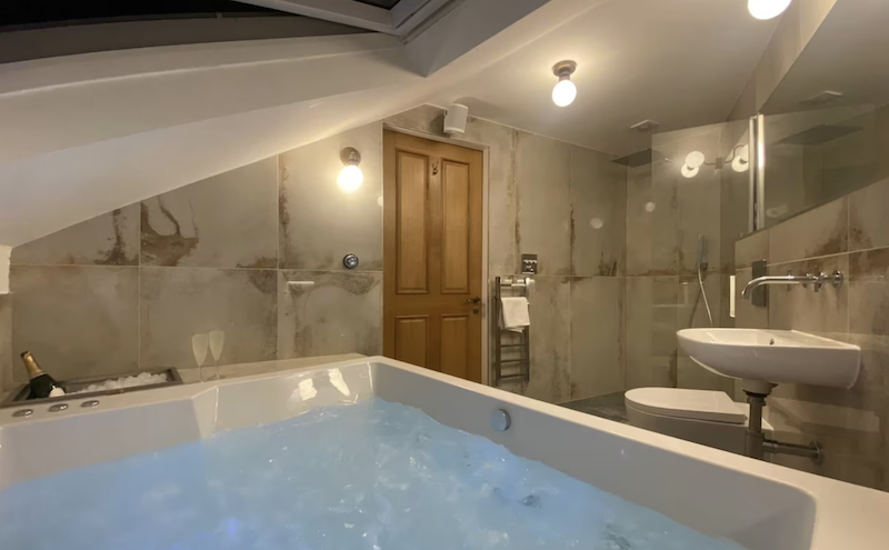 indoor white marble hot tub with a bottle of Champagne and two glasses at the Ashton View City Luxury Apartment