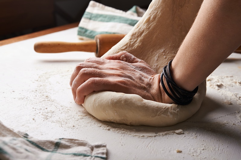 hands rolling pizza dough