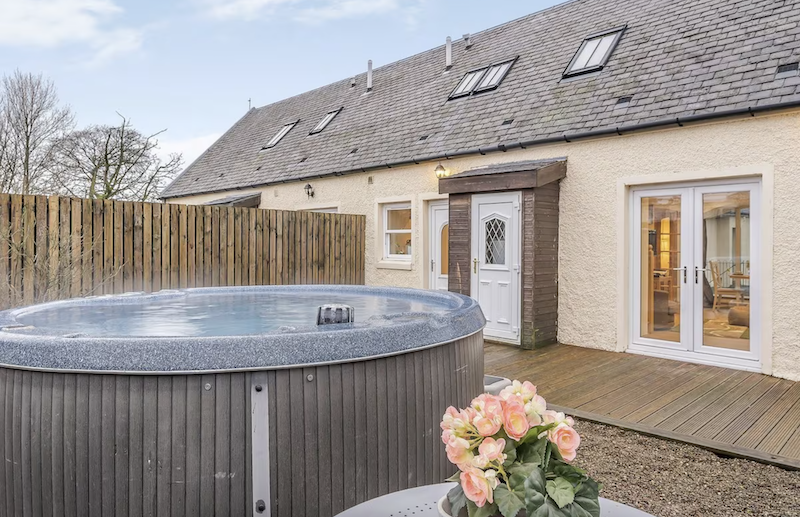 Cottage near Glasgow with an outdoor hot tub and pink flowers next to it