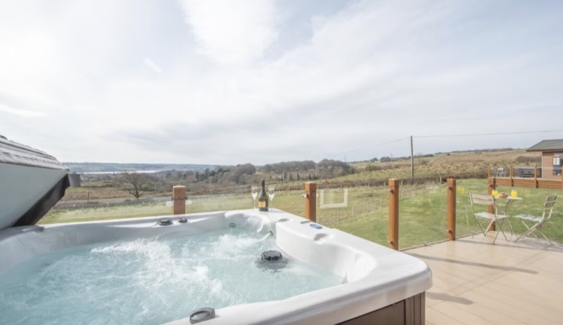 outdoor Jacuzzi with two glasses of Champagne on the rim at the Luxury Beechwood hot tub lodge in Glasgow
