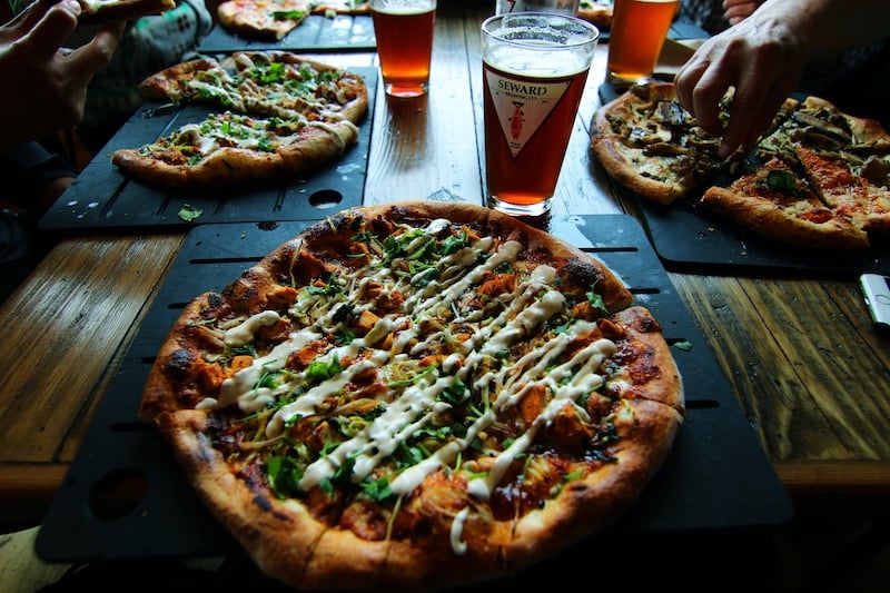 travelers eating pizza and beer on a food tour of Brooklyn