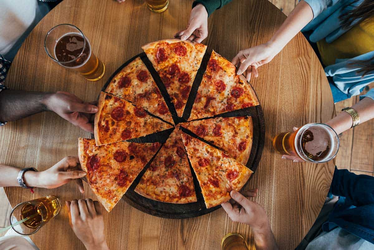 travelers eating pizza and beer on a food tour of Brooklyn