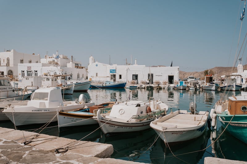 boats docked in Naoussa Harbor in Paros with white buildings in the background