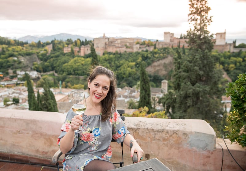solo female traveler in Spain sipping wine near the Mirador de San Nicolas in Granada