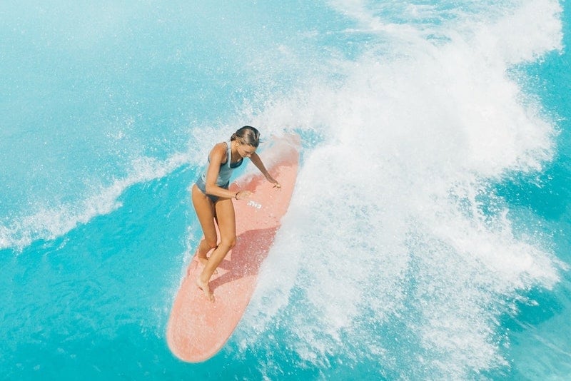 woman surfing in Bali on a pink board
