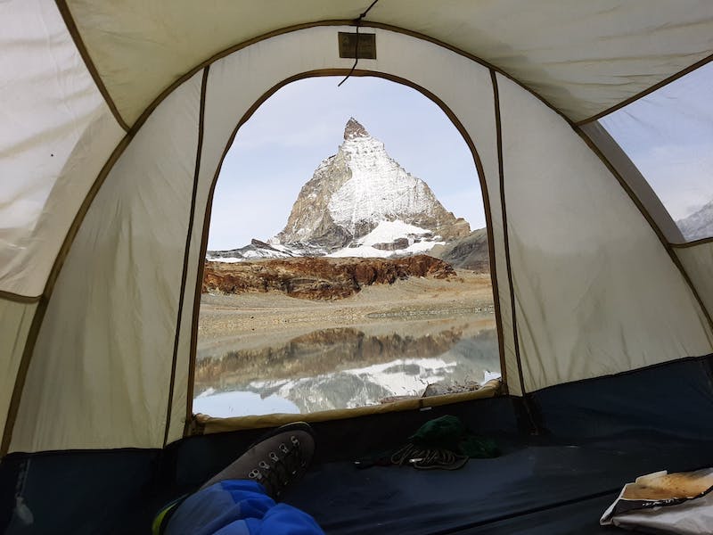 solo traveler looking at the Swiss Alps through their tent