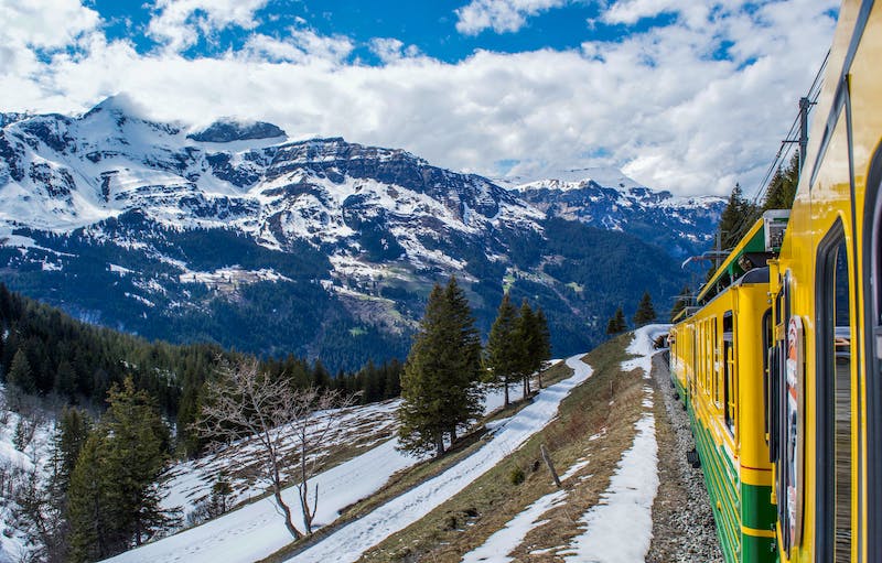yellow train riding along a mountain pass