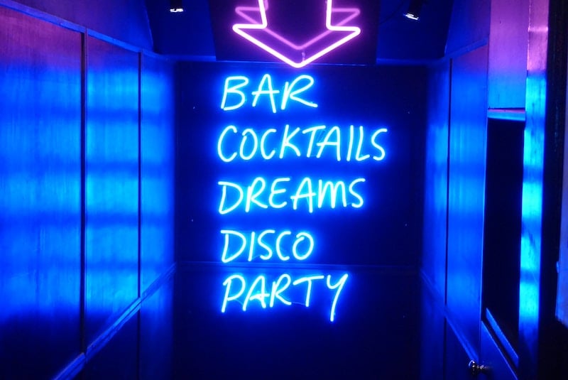 neon sign reading "Bar Cocktails Dreams Disco Party"