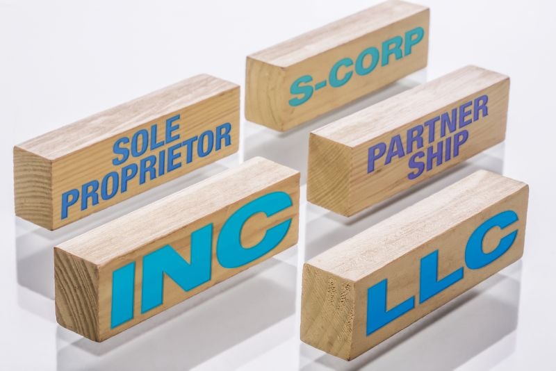 wooden blocks showcasing the various business structures bloggers can choose, like an LLC or S-Corp
