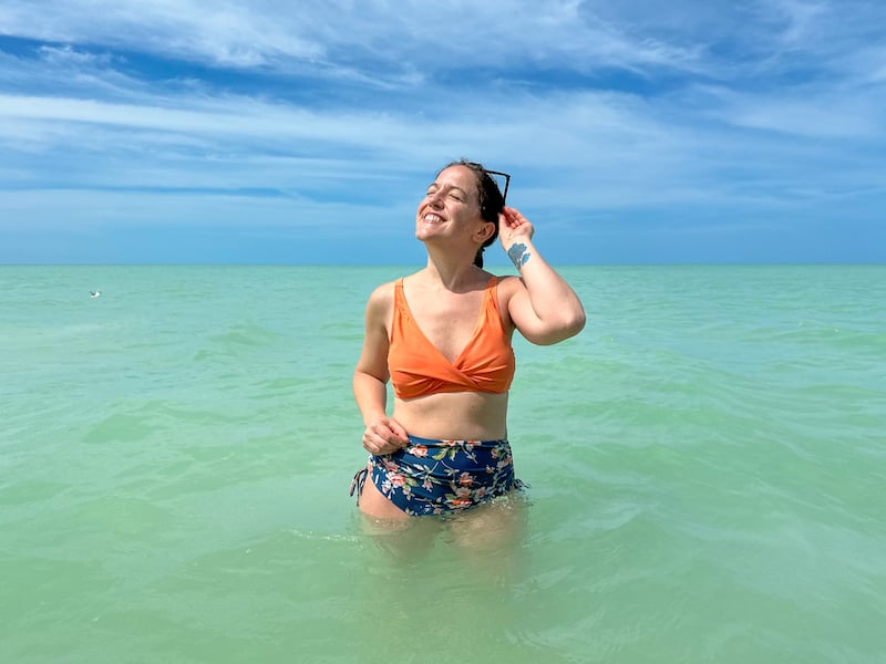 woman in an orange bikini swimming in turquoise waters in Holbox, Mexico