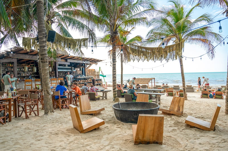 Mandarina Playa Holbox beach club with fire pit, outdoor bar, and wooden seats 