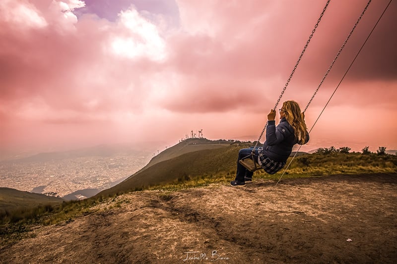 solo female traveler on a swing with a view over Quito, Ecuador