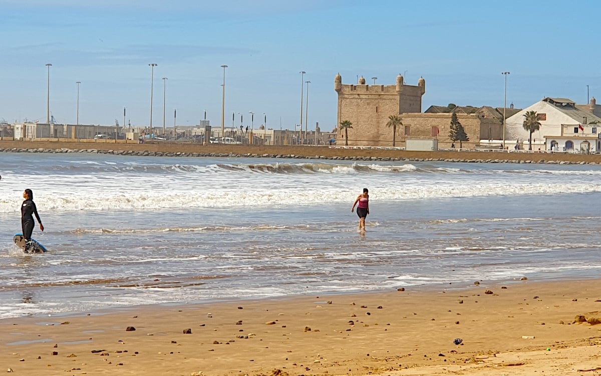 a woman walking along the coast of Essaouira Beach in Morocco