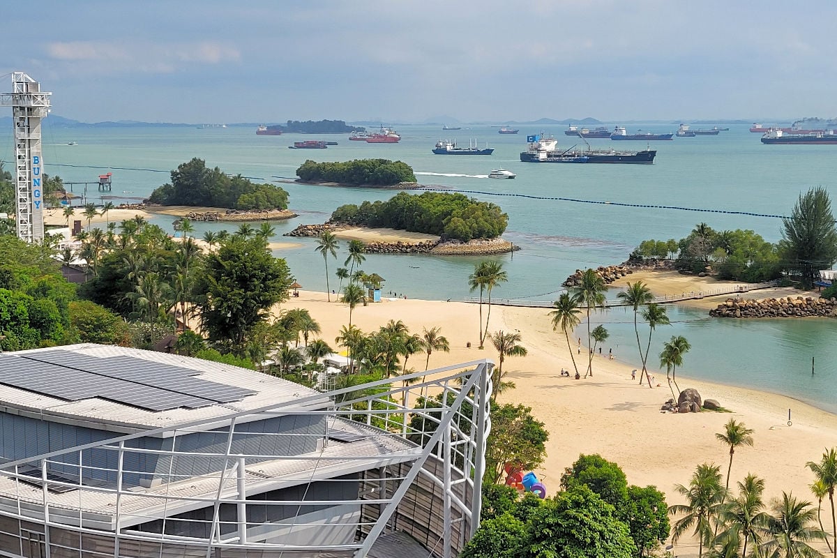 the golden sand Siloso Beach surrounded by boats and smaller islands on Sentosa Island, Singapore