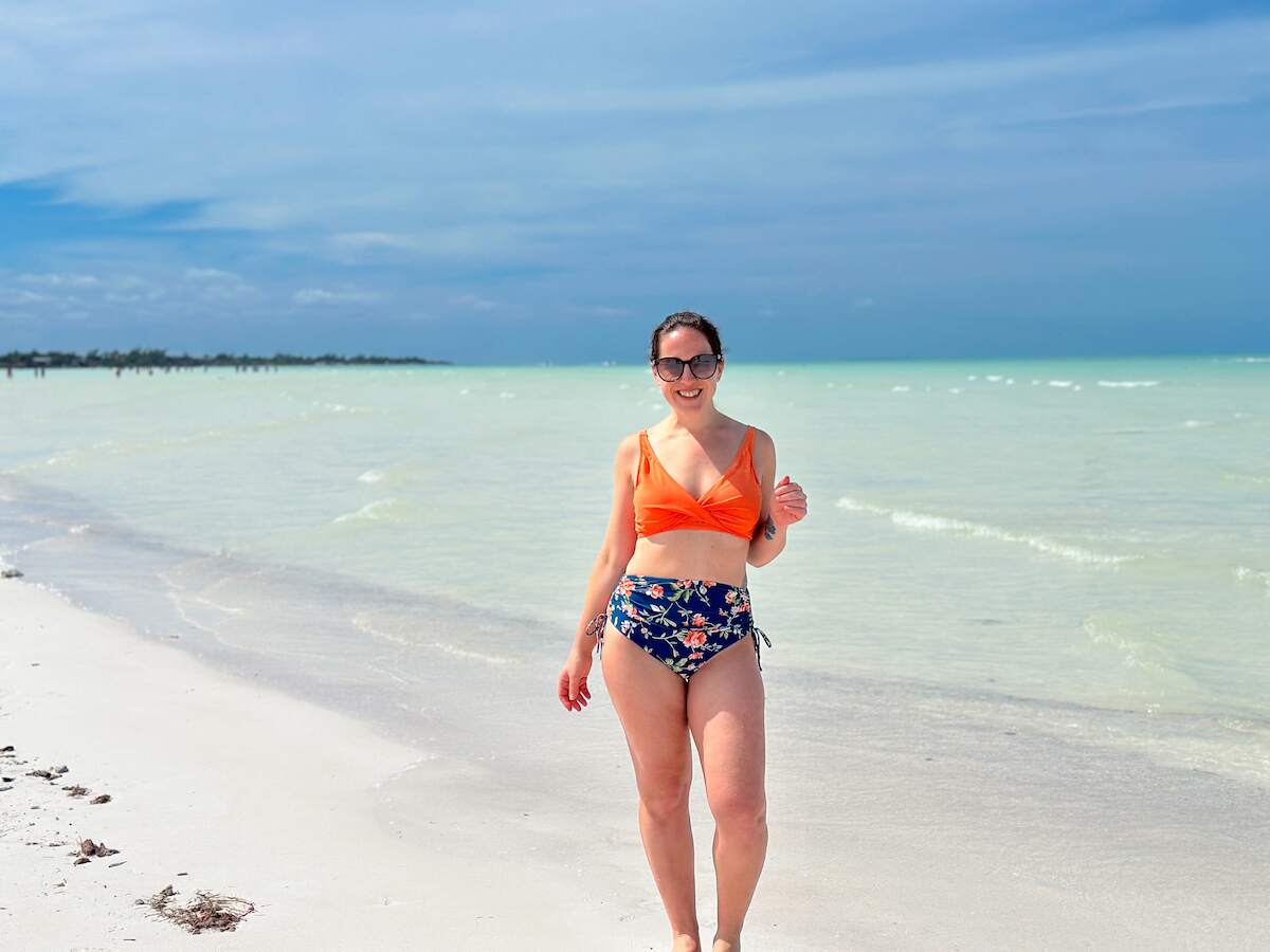 woman in an orange bathing suit walking along a white sandbar near Mosquito Point on Holbox Island, Mexico in the dry season