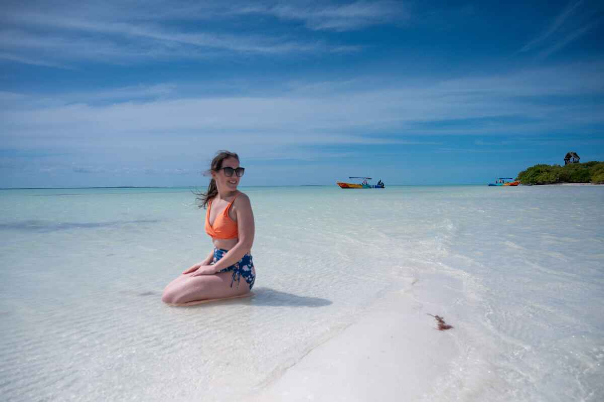 woman kneeling in the clear water off Isla Pajaros (Bird Island) near Isla Holbox on a Classic 3 Island Tour