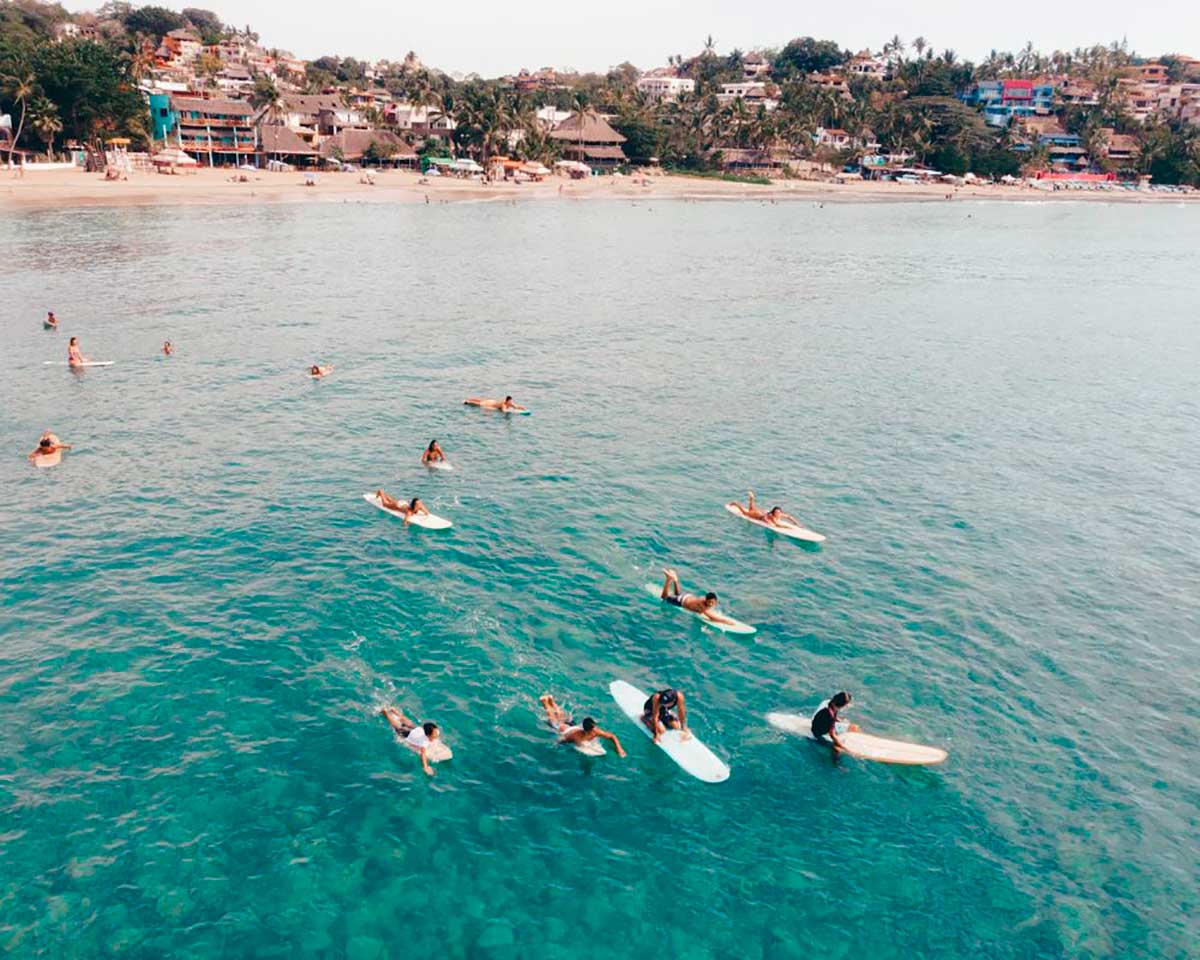surfers paddling in clear waters away from the beautiful Sayulita Beach in Mexico