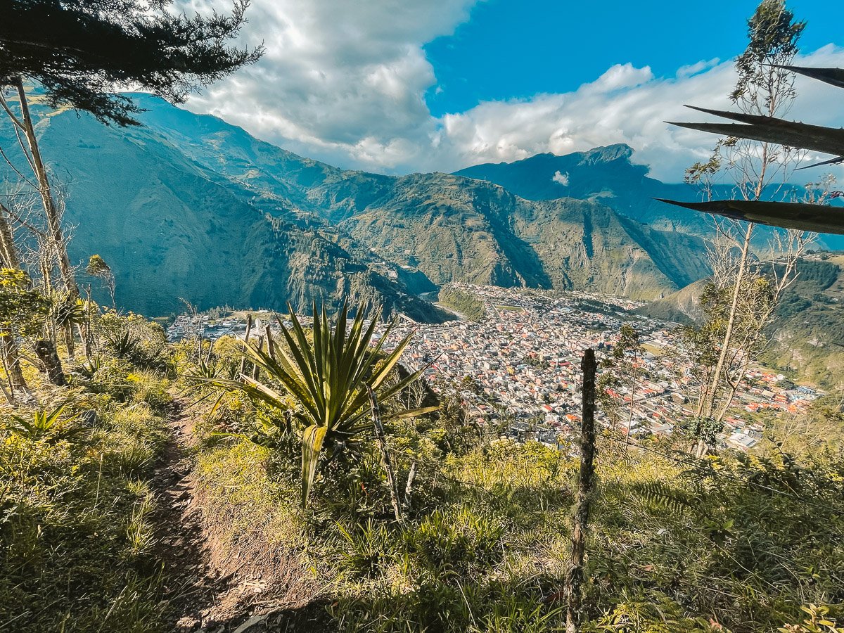 Scenic view of Baños, Ecuador, captured during the hike to the La Virgen statue, with the town nestled among the lush green mountains and dramatic landscapes, an inspiring sight for solo travelers exploring Ecuador.