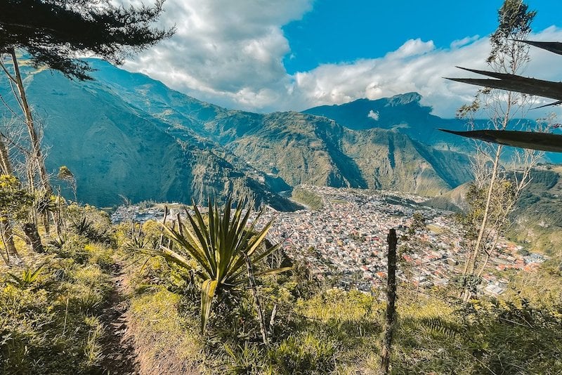 Scenic view of Baños, Ecuador, captured during the hike to the La Virgen statue, with the town nestled among the lush green mountains and dramatic landscapes, an inspiring sight for solo travelers exploring Ecuador.