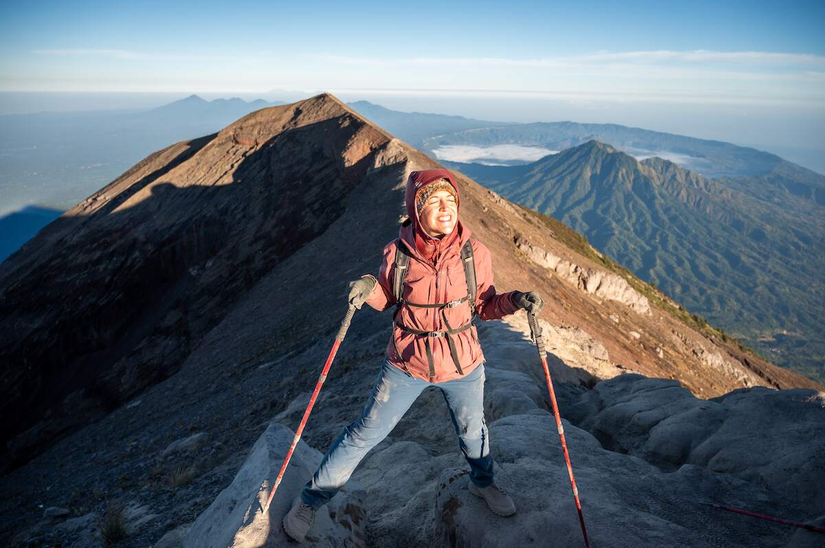 Solo female traveler celebrating at the summit of Mount Agung, the tallest mountain in Bali