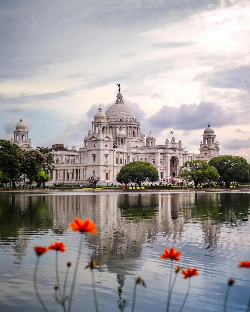 Victoria Memorial on the water with flowers in the foreground in Kolkata, India 