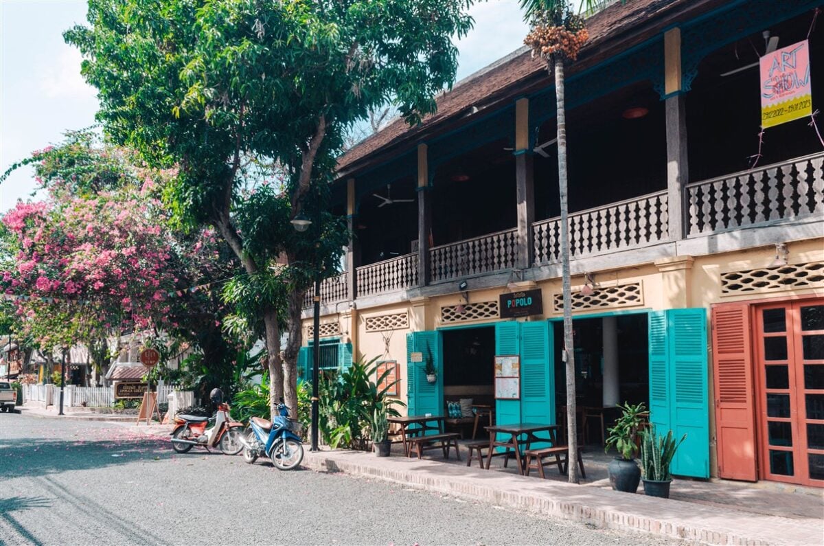 Charming street in Luang Prabang lined with colorful colonial buildings and lush trees, perfect for exploring on a solo trip to Laos.