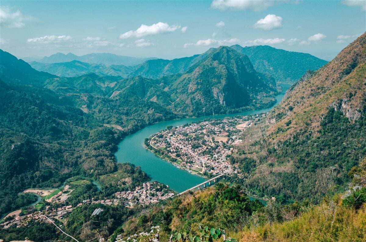 Stunning panoramic view from the top of Phadaeng Peak in Nong Khiaw, Laos, showcasing the winding river and surrounding lush green mountains.