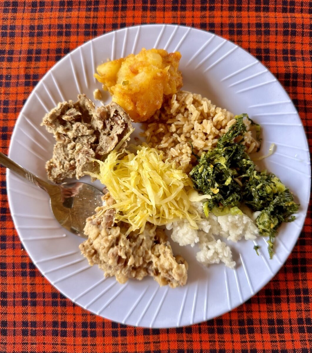 traveler eating Tanzanian food on a white plate in Rundugai Village