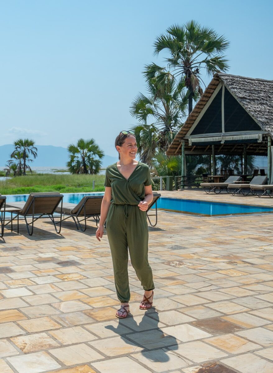 woman in a green romper walking near the pool at Maramboi Tented Lodge in Tanzania with Lake Manyara in the background