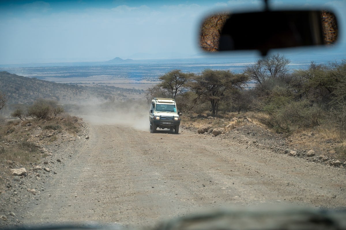 safari vehicle in Serengeti National Park in Tanzania kicking up dust