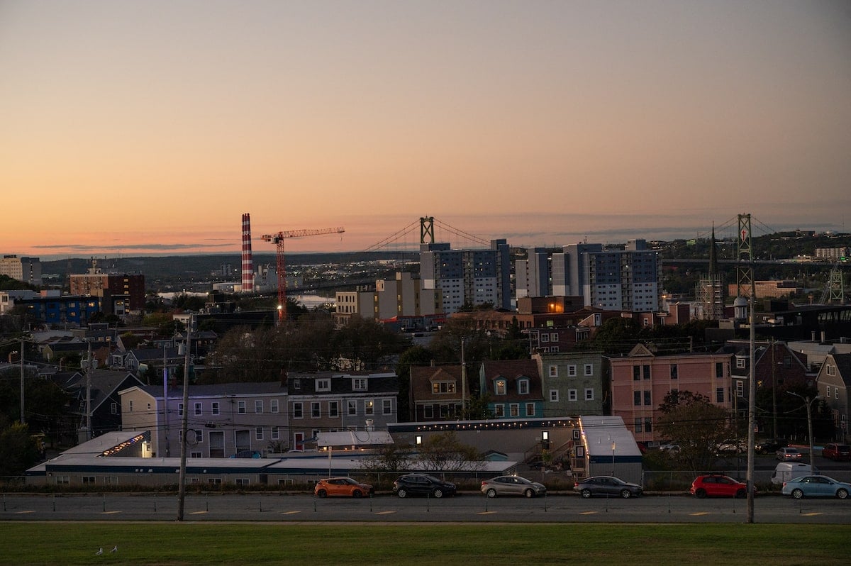 Evening view of downtown Halifax from the Halifax Citadel National Historic Site, with colorful houses, modern buildings, and the Angus L. Macdonald Bridge in the distance, just after sunset.