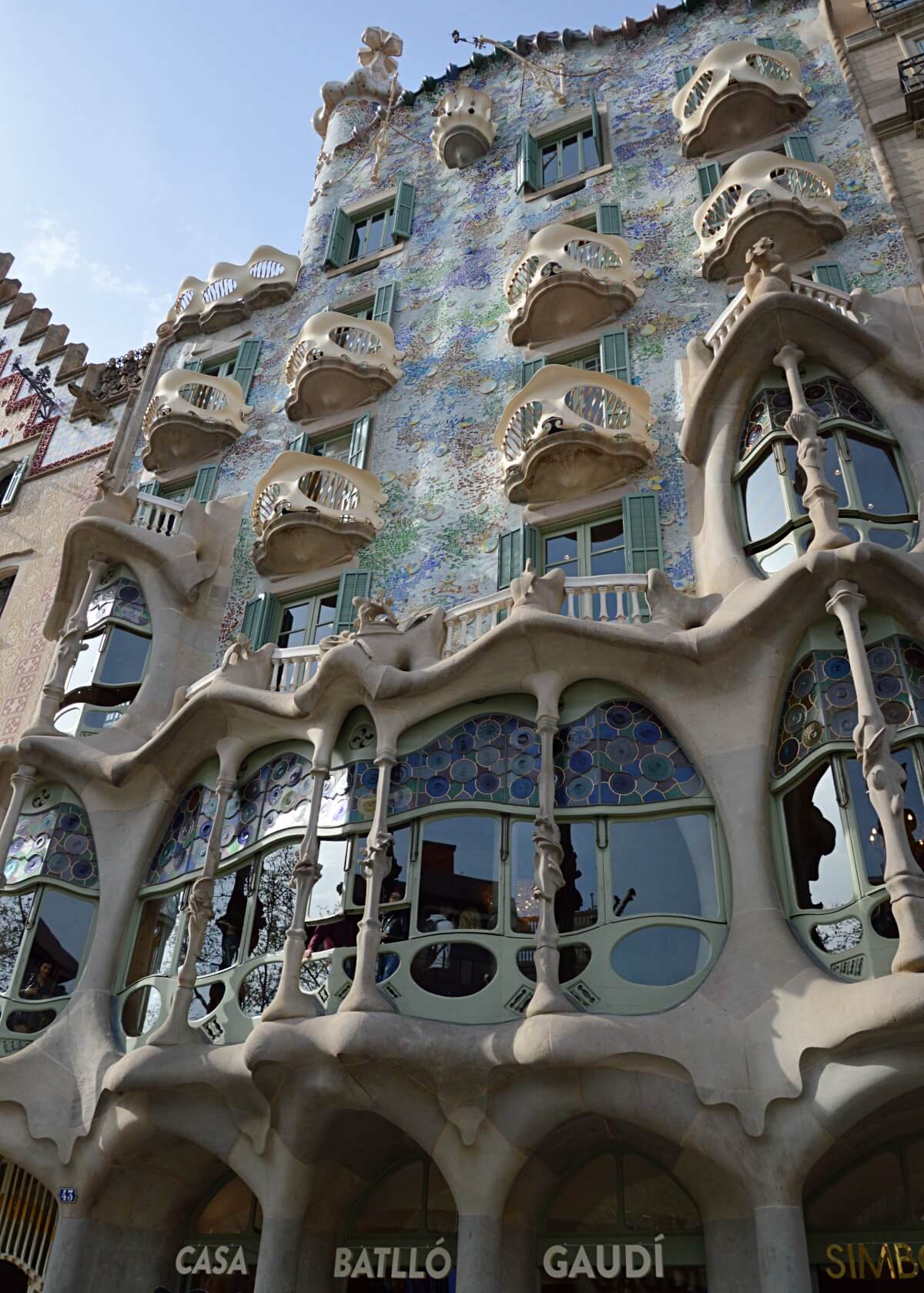 Close-up of Casa Batlló on Passeig de Gràcia in Barcelona, showcasing Gaudí's unique architecture with organic shapes, bone-like balconies, and a colorful, mosaic-covered facade.