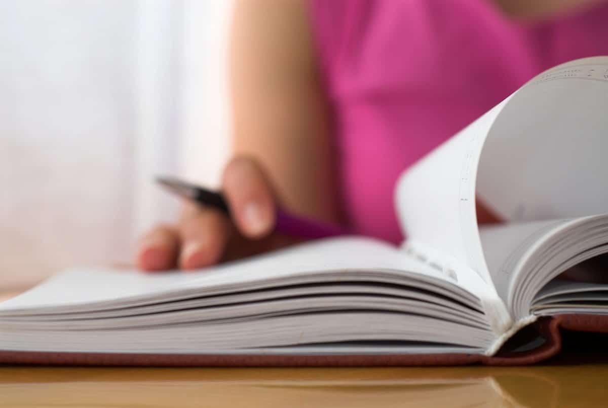 author writing her ideas for promoting her published book into a notebook