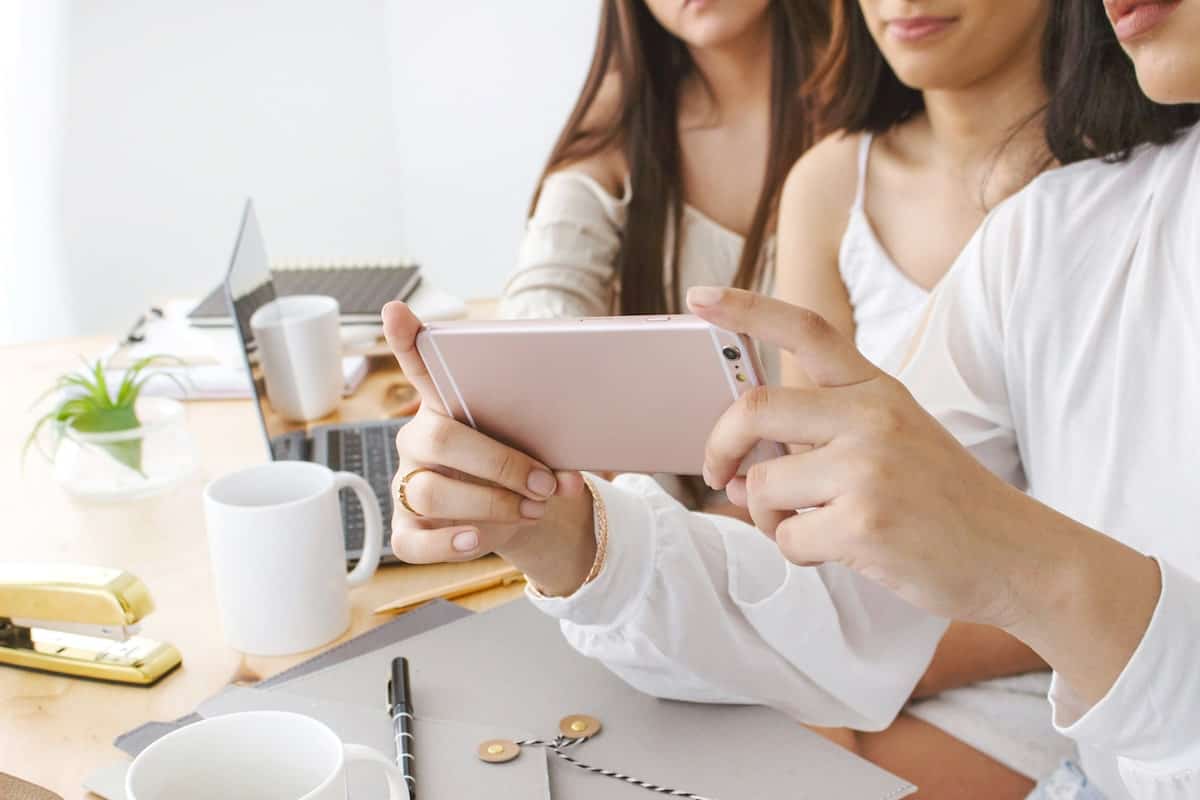 three female bloggers with their phones out collaborating to create a video series