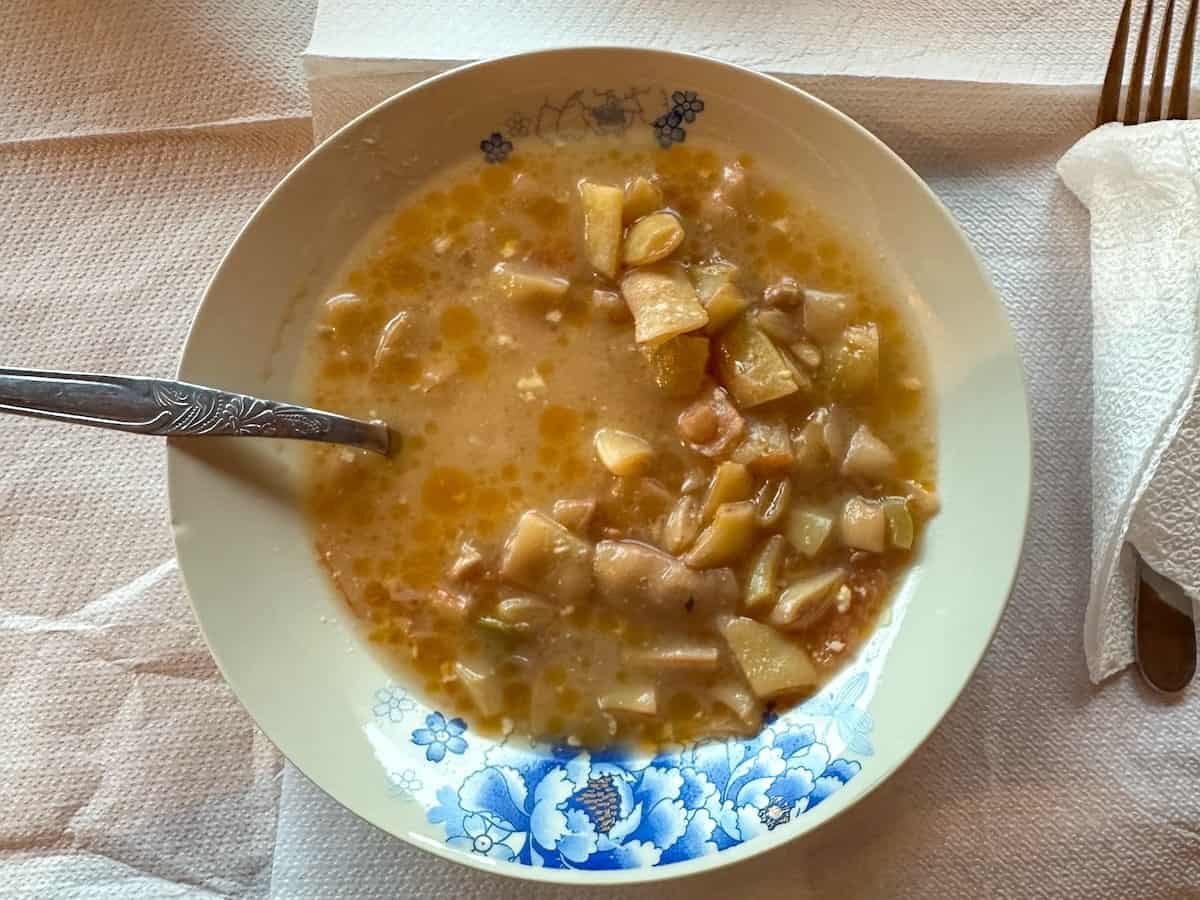 a white bowl filled with traditional Albanian White Bean Soup